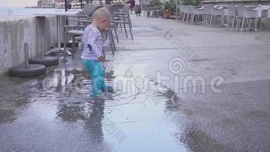 这个<strong>男孩</strong>在雨中的水坑里玩。 他在雨中快乐。 两岁的<strong>男孩</strong>在人行道上<strong>奔跑</strong>。 概念